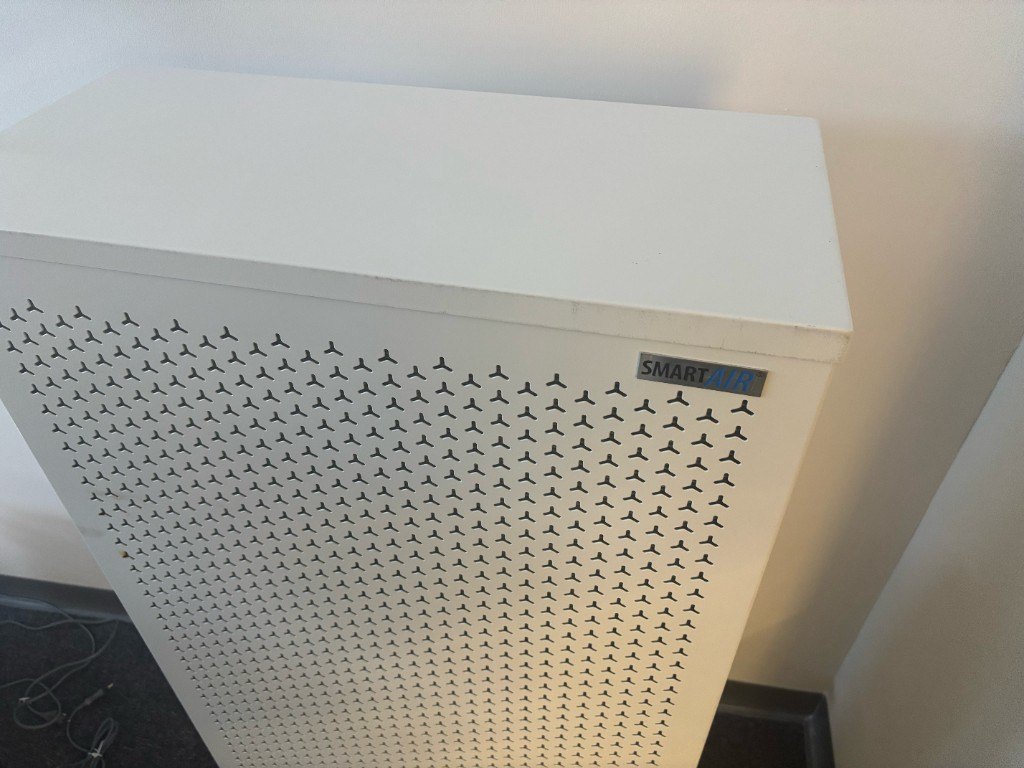 ภาพถ่ายมือถือมองลงมาที่ด้านบนของ Smart Air Blast ในมุมออฟฟิศ เห็นป้าย Smart Air และด้านหน้าเจาะรู