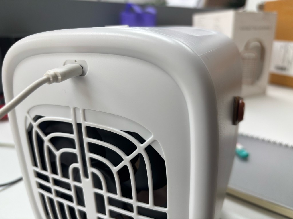 ด้านหลังของ Smart Air QT3 เสียบสาย USB ชาร์จอยู่ เห็นตะแกรงและสวิตช์ด้านข้าง