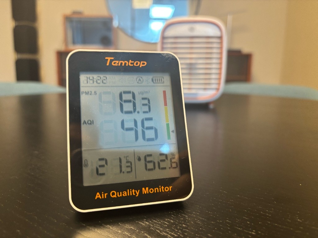 เครื่องวัดคุณภาพอากาศ Temtop แสดงค่า PM2.5 ระหว่างทดสอบอนุภาคของ QT3 โดยมี Smart Air QT3 อยู่ด้านหลัง